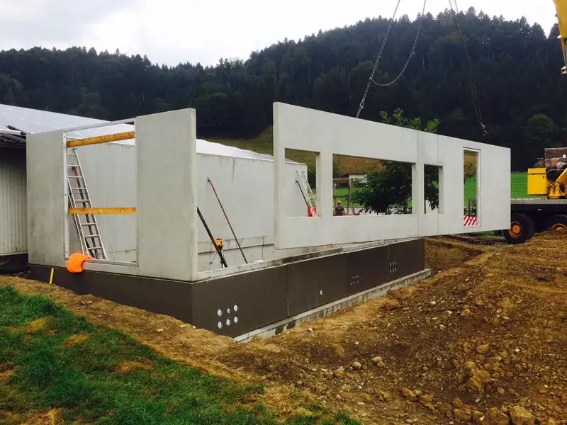 Montage einer vorfabrizierten Betonwand mit Fensteröffnungen per Kran